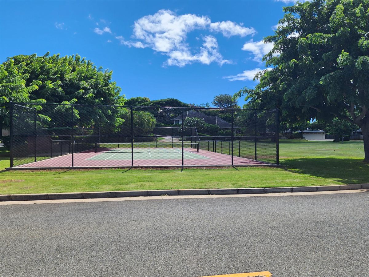 Black vinyl-coated chain link fencing around community tennis courts on Oahu